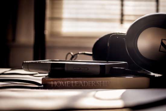 Home Leadership book underneath a phone and headphones A pair of headphones and a phone sitting on top of a book