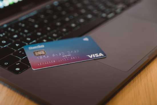 A Visa credit card sits on top of a computer.