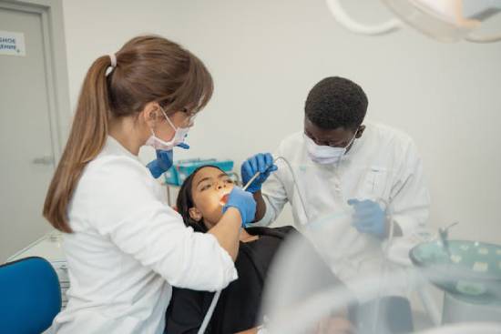 Dentist Missionaries Checking up on the Patient Image Two dentists clean a woman's teeth, illustrating how dentists can serve as medical missionaries, too.