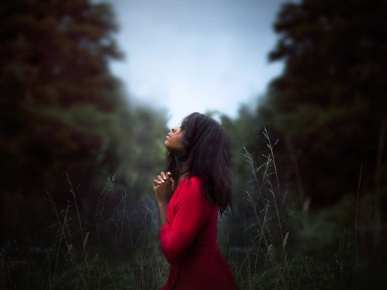 Women Praying Outside A woman folding her hands and praying for the outpouring of the Holy Spirit, which is prophesied to happen in the last days