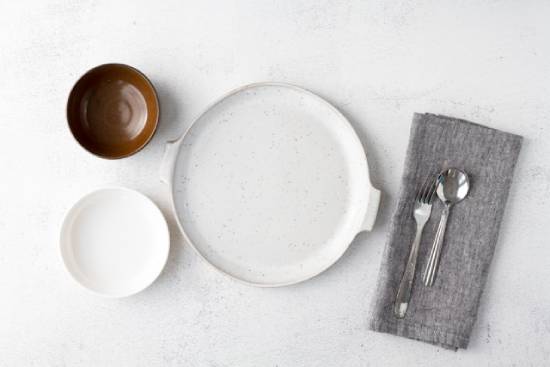 Overhead View of an Empty Plate and Bowls with Cutlery Empty plates and bowls alongside silverware, symbolizing the choice to abstain from food.