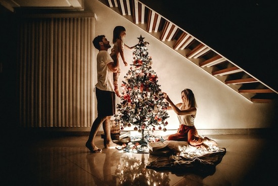 Family Decorating Tree A mother, father, and daughter decorating a Christmas tree by candlelight