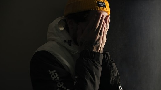 A man with his hands on his face, mourning his sin