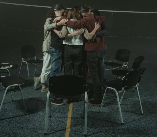 Group of young people hugging to show unity A group of Christian young adults huddled together in prayer