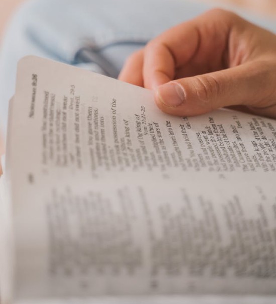 Hand holding the outside edge of an open Bible Hand holding the outside edge of an open Bible