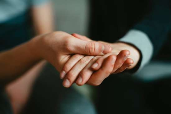 Holding hands humility A hand holding another hand with humility, offering them support