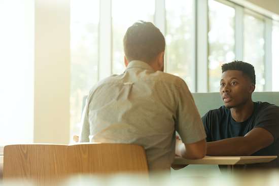 Men Listening Two seated at a table, in deep discussion