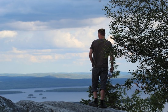Man standing on a rock overlooking the ocean  Forests and ocean landscapes are great places to visit for fresh air and relief from life's busyness.