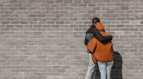 A man and woman against a brick wall reconciling and forgiving each other A man hugging a woman in forgiveness.