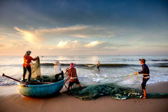 Men on the beach putting the net in the sea Fishermen pulling nets on the sea coast