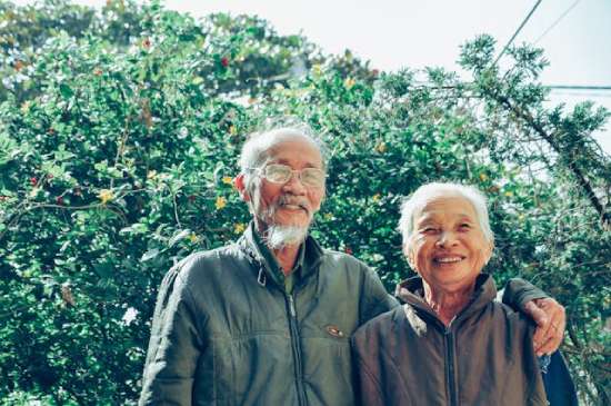 elderly couple smiling while outdoors An elderly couple standing outside enjoying nature