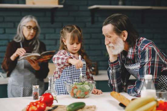 Grandparents making salad with granddaughter A young girl making a salad with her grandparents