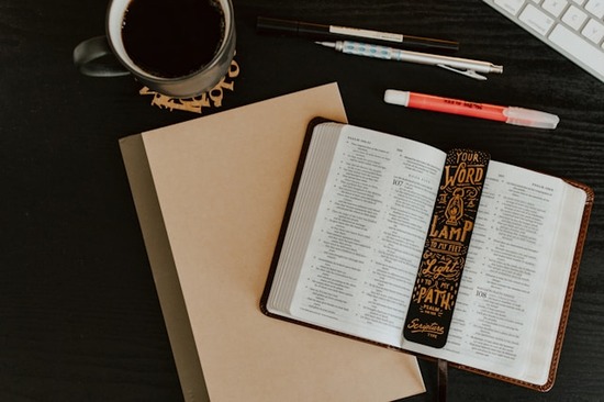 Bible study materials spread across a desk, including an open Bible with a bookmark that talks about the guidance Scripture provides.
