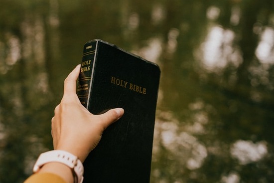Person Holding Bible up A person holding a Bible