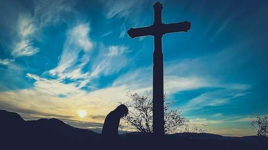 Person at Cross A man kneeling in front of a cross