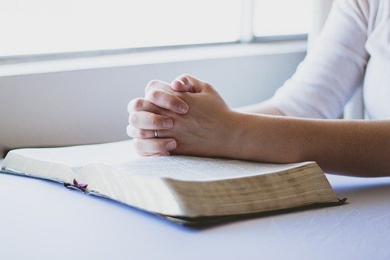 Praying Over Bible A woman with her hands folded over her Bible, praying to understand the will of God