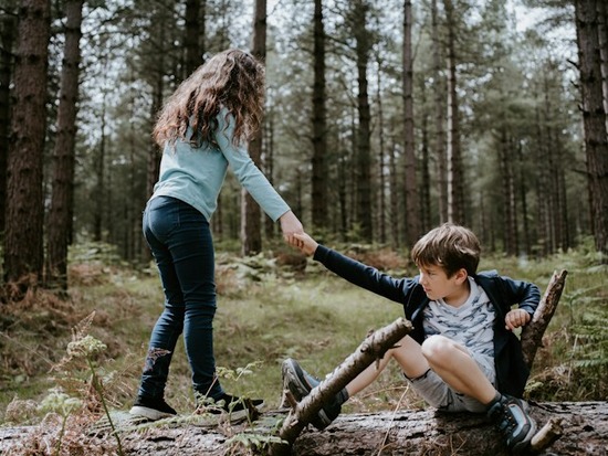 A sister showing unselfish love by giving her brother a hand after he fell