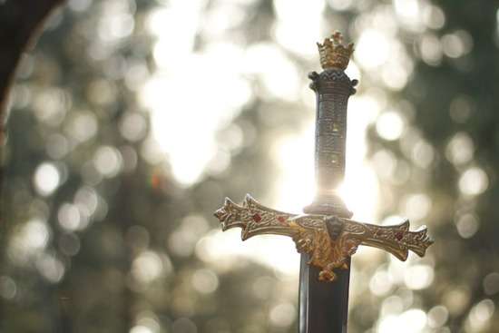 The hilt of a sword, upright, as though the sword is stuck into something. Diffuse sunlight is in the background. This sword signifies David's successful military tactics.