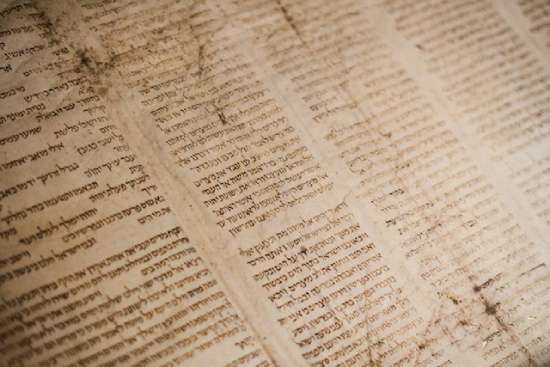 Torah An ancient page of the Torah with four columns of Hebrew writing on it.