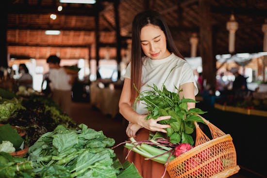 Woman buying fresh produce in a market Getting fresh produce from a local market is a great way to enhance nutrition!