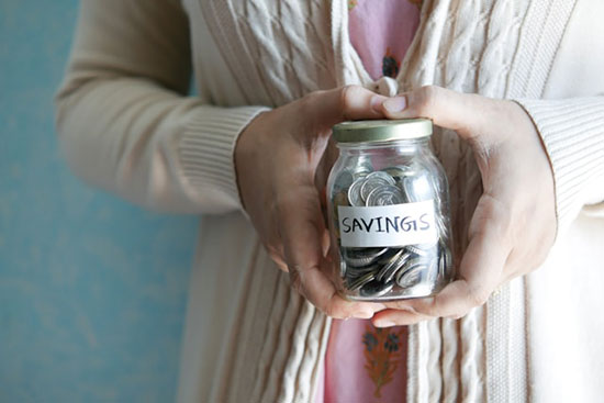 Woman Holding a Jar with Savings Written on it An image of hands hold a jar of change labeled "savings," demonstrates how we're stewards of God's resources.