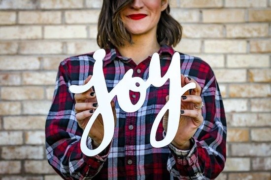 Woman holding up the word joy A woman uses her hands to frame the word "joy," one of the fruits of the Spirit.