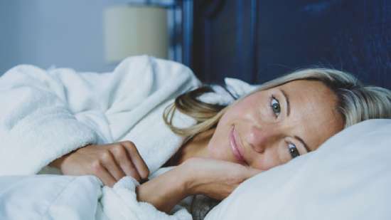Woman Relaxing Good Health A woman relaxing in bed and smiling