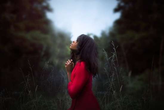 Woman praying privately in nature Woman praying in nature as we learn the importance of private prayers and time alone with God to pour our hearts to Him